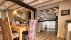 A dining area with a wooden table, chairs, and a vase of flowers. - Cosy & Spacious Cottage in Scenic Village With Pub (Ashbourne)