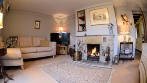 A cozy living room with a fireplace, a sofa, a television, and a rug. - Cosy & Spacious Cottage in Scenic Village With Pub (Ashbourne)