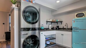 Una cocina moderna con electrodomésticos de acero inoxidable, un refrigerador verde azulado y una lavadora-secadora integrada.