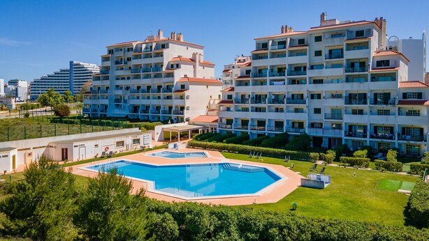 A hotel with multiple floors, a swimming pool, and a well-maintained garden.