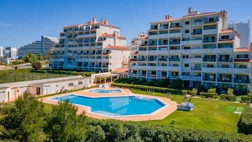 A hotel with multiple floors, a swimming pool, and a well-maintained garden.