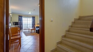 A staircase leading to a living area with a sofa, a coffee table, and a TV.
