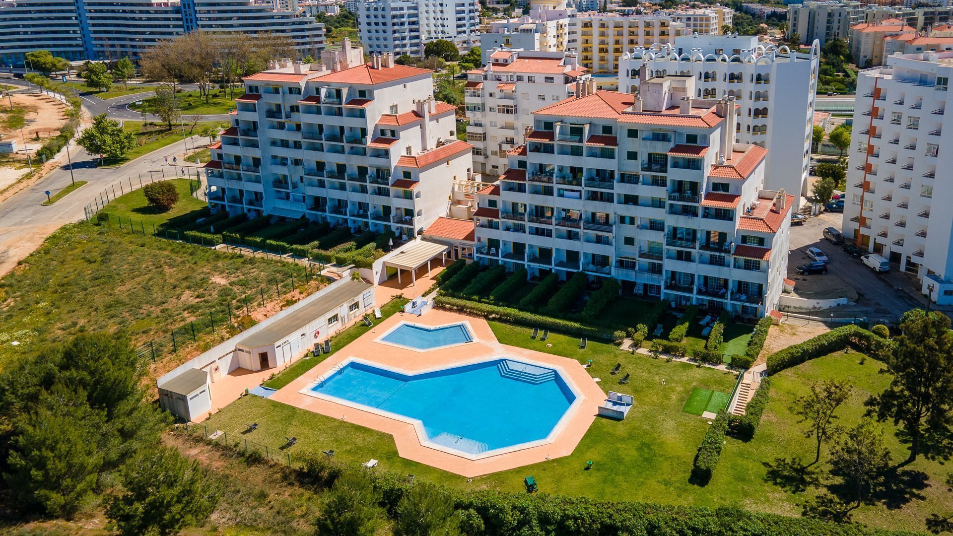 A high-rise residential building with a swimming pool and landscaped gardens.