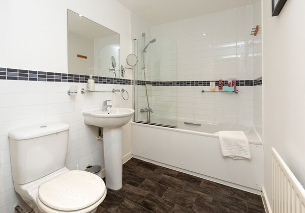 Bathroom features a toilet, pedestal sink, and glass-enclosed shower area.