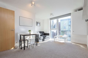A modern living room with a sofa, a coffee table, a small table, and a radiator.