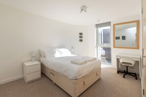 Cozy retreat with a neatly made bed, bedside table, and large mirror.