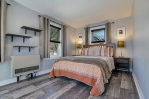A bedroom with a bed, bedside tables, a radiator, and built-in shelves.