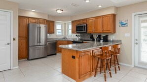 A modern kitchen with wooden cabinets, stainless steel appliances, and a granite countertop.