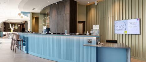 A reception area with a blue counter, a wheelchair accessibility sign, and a sign for B&B Hotels.