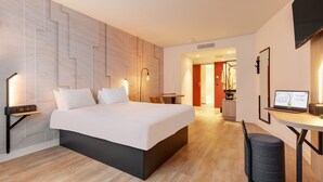 A modern hotel room with a large bed, bedside tables, a desk with a laptop, and a TV. - B&B HOTEL Lille Lillenium Eurasanté (Lille)