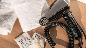 A hair dryer, a white towel, and two pamphlets on a wooden surface.