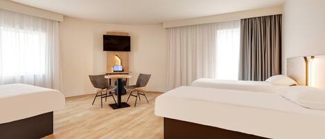 Habitación de hotel con dos camas, un escritorio con silla, un televisor de pantalla plana y ventanas amplias con cortinas.
