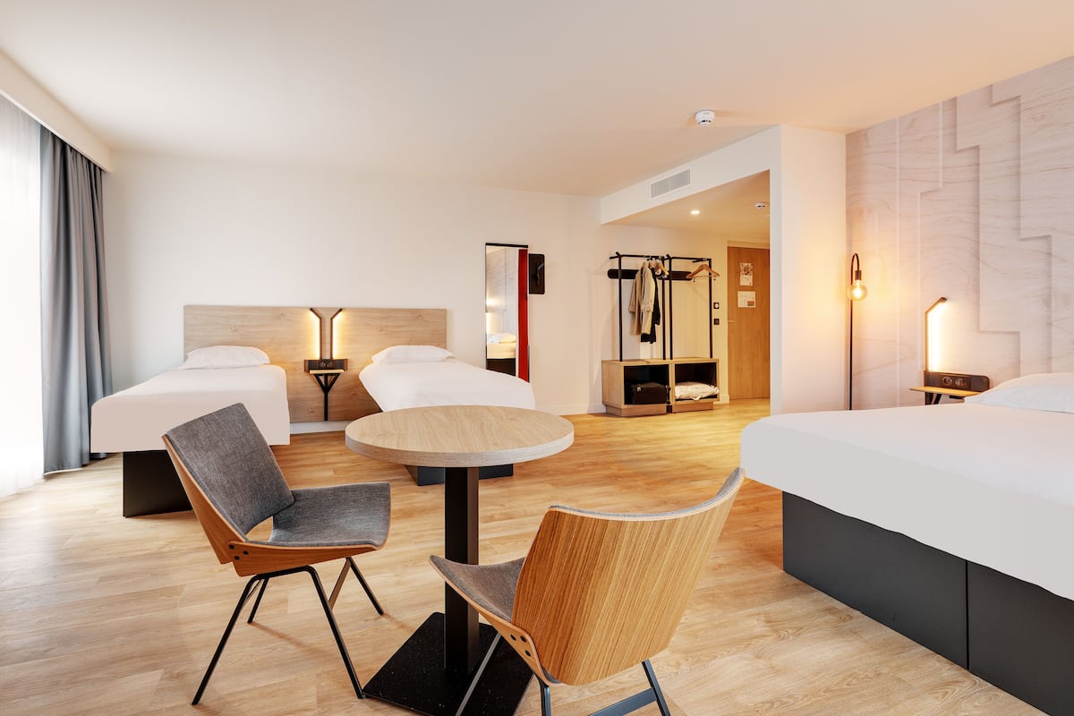 Hotellihuone, jossa on kaksi sänkyä, pyöreä pöytä ja kaksi tuolia.