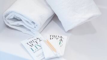 A white bathroom sink with two rolled-up white towels and a magazine titled "Think & Act".