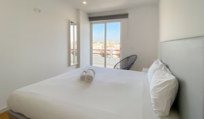 Ein Hotelzimmer mit Bett, Stuhl und Fenster mit Blick auf Gebäude.