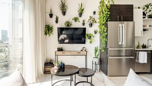 Eine moderne Küche mit einem großen Kühlschrank, einem Esstisch mit zwei Stühlen und einem an der Wand befestigten Fernseher.