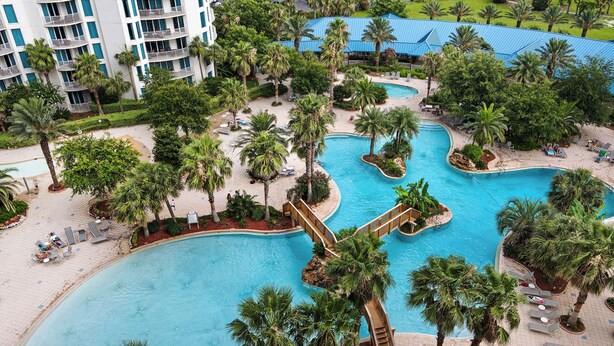 A resort with multiple swimming pools surrounded by palm trees and lounge areas.
