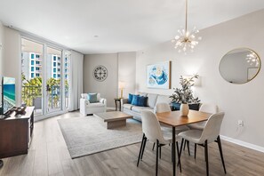 Sala moderna com área de jantar, janelas amplas e vista para um edifício com varandas.