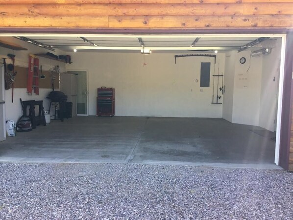 Un garage avec un sol en béton, un établi et divers outils et équipements.