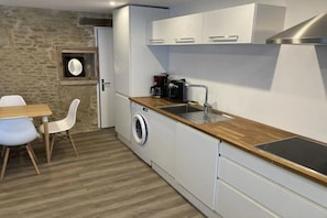 A compact kitchen with a washing machine, a coffee maker, and a sink. - Ornella's house (Courseulles-sur-Mer)
