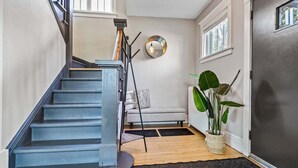 A staircase with a dark finish, a light-colored sofa, a large plant, and a window with a view.
