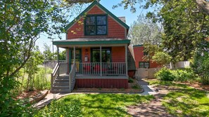 A two-story house with a porch, a small front yard, and a wooden fence.
