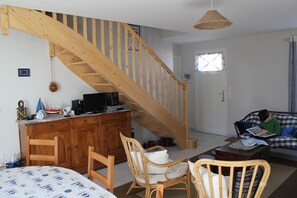 A living room with a wooden staircase, a sofa, a coffee table, and a dining table with chairs.