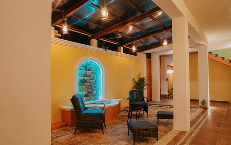 A lobby with a stone floor, a fountain, wicker furniture, and a staircase.
