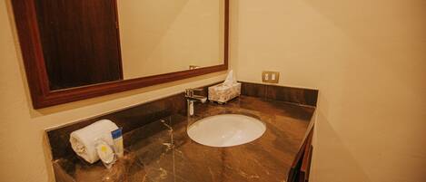 Un baño con lavamanos de mármol, una toalla y una caja de pañuelos.