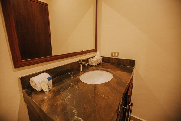 A bathroom with a marble sink, a towel, and a tissue box. - Hotel Beach Don Gonzalo (Celestún)