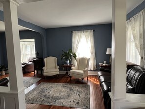 Uma sala de estar com parede azul, dois poltronas, uma mesa de centro, um tapete e um sofá de couro.