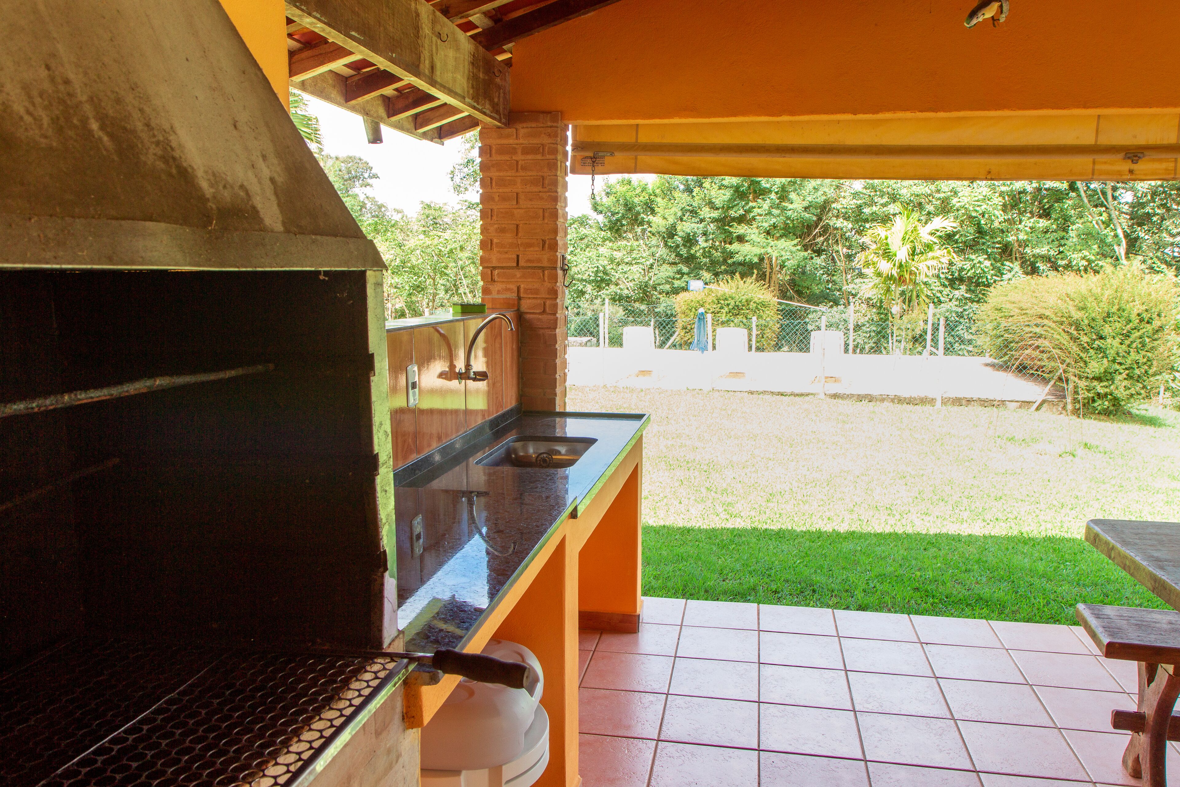 Un área de cocina exterior con una parrilla, un fregadero y una mesa de comedor.