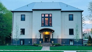 A two-story building with a symmetrical facade, large windows, and a central entrance with steps. - The Hemlock Loft (Boyne City)