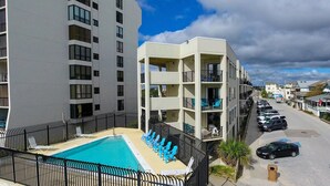 A modern apartment building with a rooftop pool and lounge chairs. - Ocean Views, Balcony, Pool, STEPS to Beach, Restaurants, Shops (Wrightsville Beach)