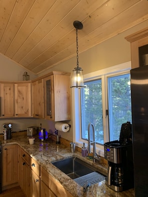 Enjoy cooking in this well-equipped kitchen with a granite countertop, stainless steel sink, and wooden cabinets.