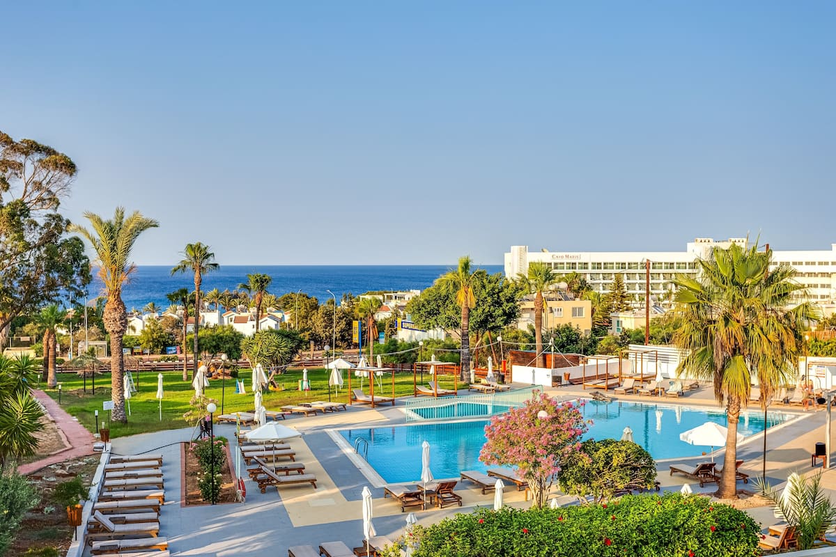 A resort pool area with lounge chairs, umbrellas, and a view of the ocean.