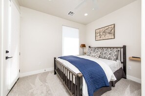 Un dormitorio con una cama individual, una ventana con persianas, un mapa colgado en la pared y un ventilador de techo.