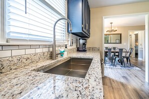 A kitchen with a granite countertop, stainless steel sink, and a window with blinds. - NEW! Fully stocked luxury home 5 min to I-65/I-72. (Athens)