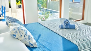 Een bed met een blauw-wit beddekleed, een opgerolde handdoek en een kussen met een blauw bloemenmotief.