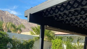 En pool med solstolar, en pergola och utsikt över bergen.