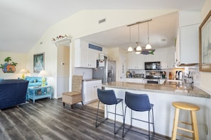 Relax in this open-plan living and dining area with a kitchen, featuring a large island and bar stools.