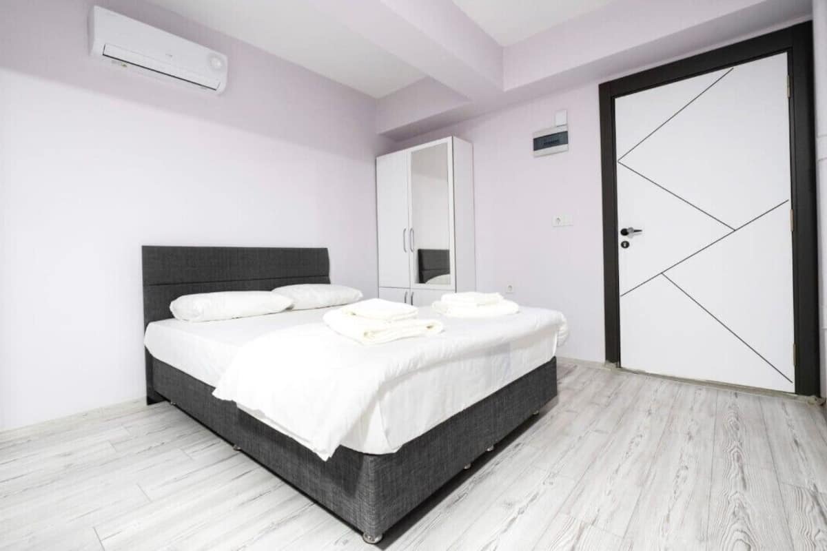 A bedroom with a bed, a wardrobe, a mirror, and a door.