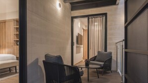 A modern interior with a sofa, two chairs, a small table, and a TV in a room with wooden flooring and walls. - Leonora Boutique Stays by Viadora (Mexico City)