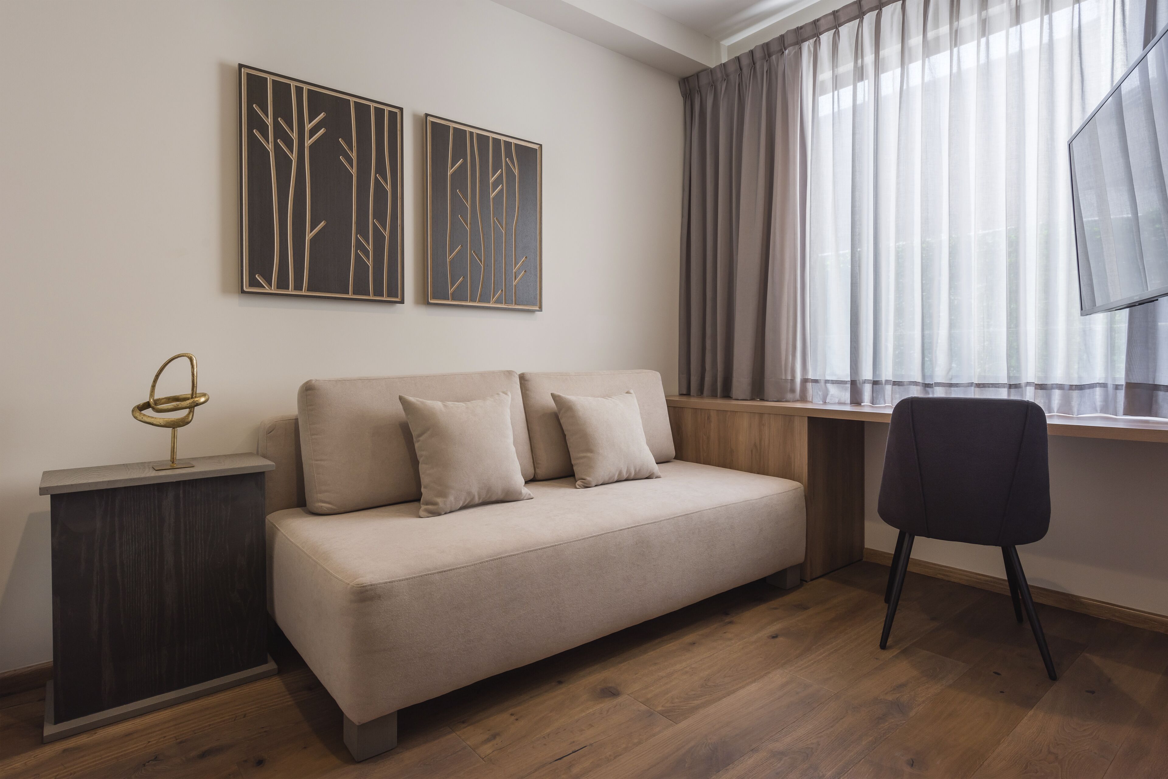 Een moderne woonkamer met een bank, een bijzettafeltje, een stoel en kunst aan de muur.