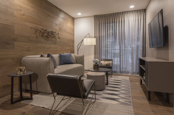 A modern living room with a sofa, armchair, coffee table, and TV. - Leonora Boutique Stays by Viadora (Mexico City)