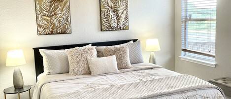 Una camera da letto con un letto, due lampade a parete, una ventola a soffitto e una finestra con tende.