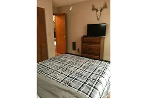 Ein Schlafzimmer mit Bett, Kommode, Fernseher und Wanddeko.