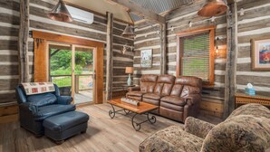 L’intérieur d’une cabane en rondins, avec un canapé en cuir, un fauteuil bleu et un canapé à motifs.