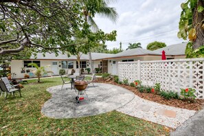 A backyard with a barbecue grill, patio furniture, and a white fence.