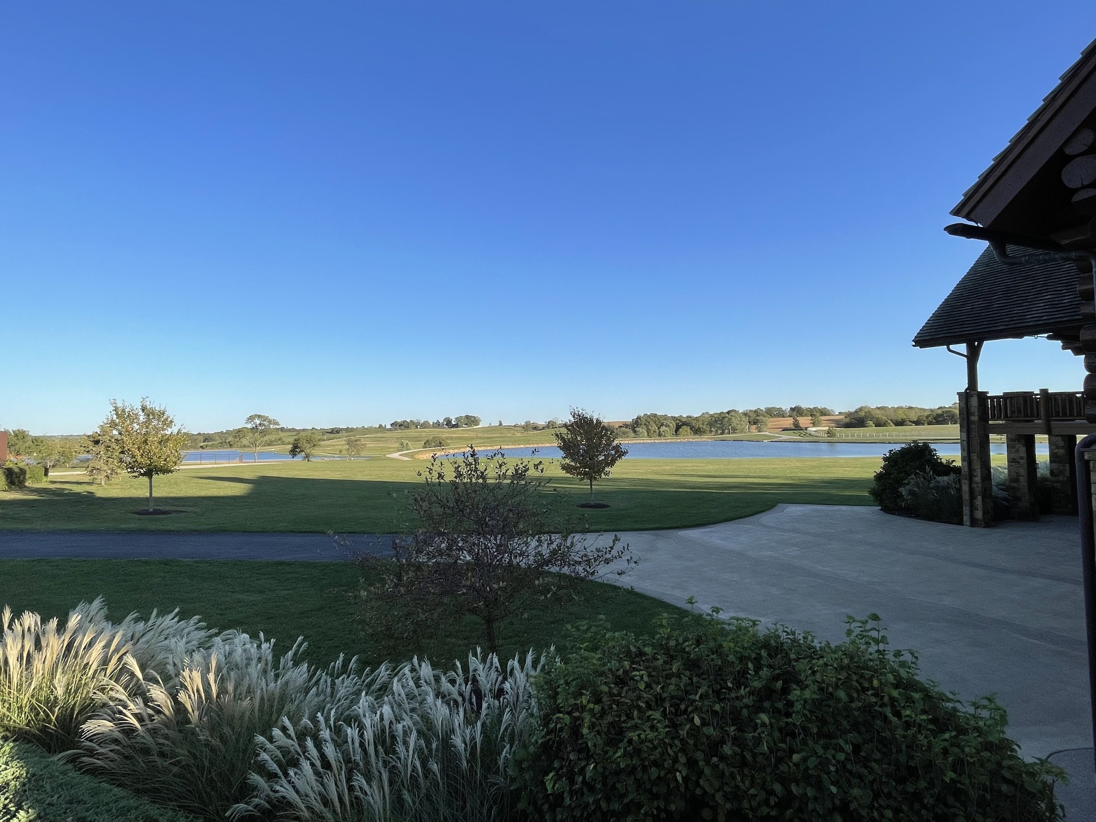 A view of a golf course with a clear sky, a body of water, and a gazebo structure.